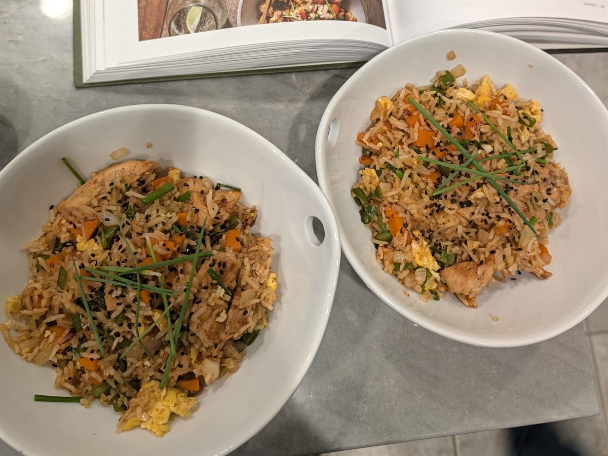 Two bowls of chicken fried rice topped with scallions and black sesame